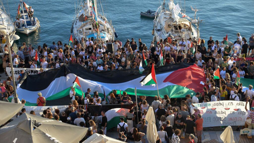 A Palestinian flag is seen as people gather at the port of Ermoupolis before the departure of two sailing boats, Electra and Oxygen, part of the Global Sumud Flotilla aiming to reach Gaza and break Israel's naval blockade, on Syros island, Greece, September 14, 2025.